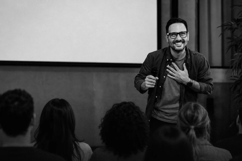 A man speaks confidently in front of an audience.